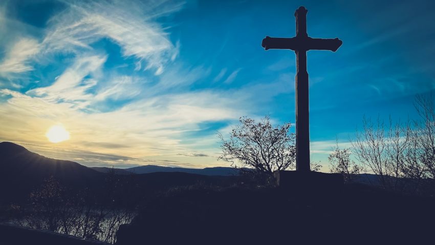 a cross on top of a hill with a sky background